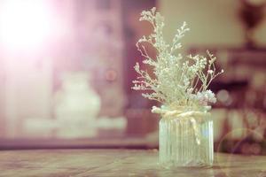 fiori secchi in vaso di vetro con corda su sfondo sfocato foto
