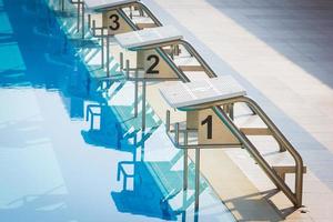 una fila di blocchi di partenza della piscina a bordo piscina. orizzontale foto