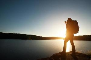sagoma di uomo escursionista con zaino in montagna paesaggio al tramonto. foto