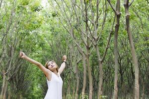 giovane bella donna ha alzato le braccia godendosi il fresco nella foresta verde. foto