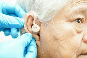 medico installare udito aiuto su anziano paziente orecchio per ridurre udito perdita problema. foto