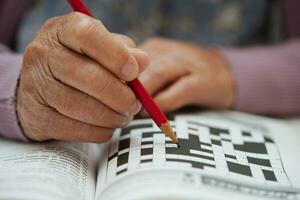 asiatico anziano donna giocando sudoku puzzle gioco per pratica cervello formazione per demenza prevenzione, alzheimer patologia. foto
