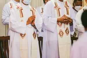 cattolico sacerdote nel tradizionale Abiti battimani mani durante un' religioso cerimonia. foto