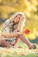 attraente giovane donna con sensuale Sorridi seduta nel autunno parco foto