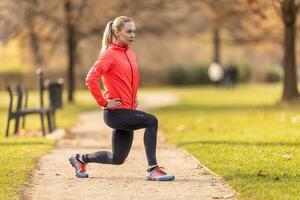 un' giovane donna riscalda su prima jogging e riscalda su sua gamba muscoli foto