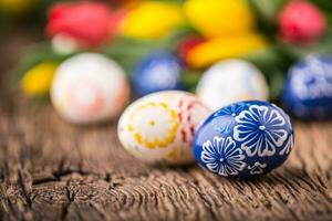 Pasqua. mano fatto Pasqua uova e primavera tulipani su vecchio di legno tavolo. foto