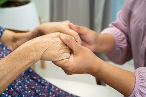 badante Tenere mani asiatico anziano donna paziente con amore, cura, incoraggiare e empatia nel parco, salutare forte medico concetto. foto