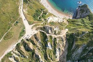 alto angolo Visualizza di persone siamo si avvicina per durdle porta spiaggia quale è maggior parte famoso turista attrazione posto attraverso a piedi distanza al di sopra di paesaggio e colline. catturato su settembre 9, 2023 foto