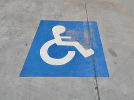cartello blu sull'asfalto del parcheggio per disabili foto