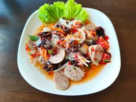 insalata piccante di salsiccia vietnamita su piatto bianco foto