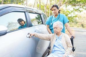 aiutare e supportare una paziente asiatica anziana su sedia a rotelle per raggiungere l'auto