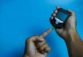 uomo controllo sangue zucchero livello utilizzando glucometro. diabete concetto su blu sfondo foto
