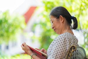 donna asiatica anziana che utilizza tablet nel giardino di casa. concetto di tecnologia foto