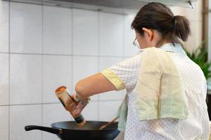 donna asiatica anziana che cucina pasta per pranzo in cucina?