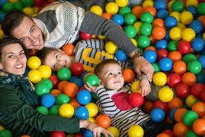 genitori e bambini giocando nel il piscina con colorato palle foto