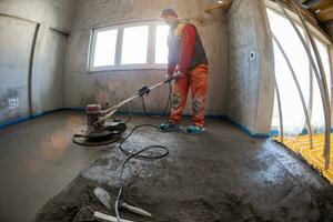 lavoratore l'esecuzione e lucidatura sabbia e cemento massetto pavimento foto