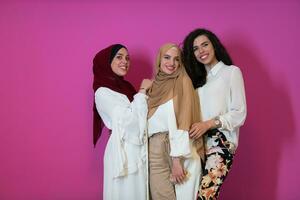 gruppo ritratto di bellissimo musulmano donne Due di loro nel alla moda vestito con hijab isolato su rosa sfondo che rappresentano moderno Islam moda e Ramadan kareem concetto foto