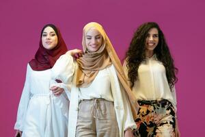 gruppo ritratto di bellissimo musulmano donne Due di loro nel alla moda vestito con hijab isolato su rosa sfondo che rappresentano moderno Islam moda e Ramadan kareem concetto foto