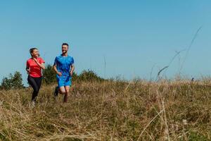 coppia godendo nel un' salutare stile di vita mentre jogging su un' nazione strada attraverso il bellissimo soleggiato foresta, esercizio e fitness concetto foto