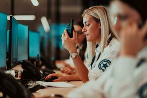 femmina sicurezza operatore Tenere portatile Radio nel mano mentre Lavorando nel un' dati sistema controllo camera uffici tecnico operatore Lavorando a stazione di lavoro con multiplo mostra, sicurezza guardia Lavorando su foto