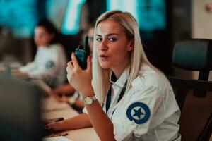 femmina sicurezza operatore Tenere portatile Radio nel mano mentre Lavorando nel un' dati sistema controllo camera uffici tecnico operatore Lavorando a stazione di lavoro con multiplo mostra, sicurezza guardia Lavorando su foto