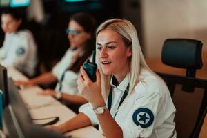 femmina sicurezza operatore Tenere portatile Radio nel mano mentre Lavorando nel un' dati sistema controllo camera uffici tecnico operatore Lavorando a stazione di lavoro con multiplo mostra, sicurezza guardia Lavorando su foto