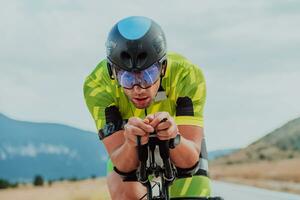 vicino su foto di un attivo triatleta nel abbigliamento sportivo e con un' protettivo casco equitazione un' bicicletta. selettivo messa a fuoco