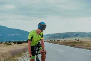 vicino su foto di un attivo triatleta nel abbigliamento sportivo e con un' protettivo casco equitazione un' bicicletta. selettivo messa a fuoco