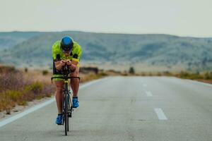 pieno lunghezza ritratto di un attivo triatleta nel abbigliamento sportivo e con un' protettivo casco equitazione un' bicicletta. selettivo messa a fuoco foto