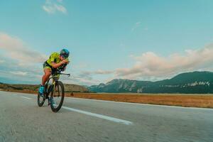 pieno lunghezza ritratto di un attivo triatleta nel abbigliamento sportivo e con un' protettivo casco equitazione un' bicicletta. selettivo messa a fuoco foto