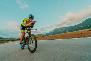 pieno lunghezza ritratto di un attivo triatleta nel abbigliamento sportivo e con un' protettivo casco equitazione un' bicicletta. selettivo messa a fuoco foto