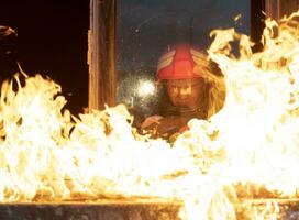 pompiere eroe trasporto bambino ragazza su a partire dal ardente edificio la zona a partire dal fuoco incidente. salvare persone a partire dal pericoloso posto foto