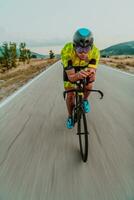 pieno lunghezza ritratto di un attivo triatleta nel abbigliamento sportivo e con un' protettivo casco equitazione un' bicicletta. selettivo messa a fuoco foto