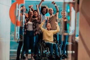 foto di attività commerciale donne nel sedie a rotelle con loro mani sollevato nel il aria con loro colleghi, insieme festeggiare attività commerciale successo