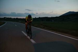 atleta di triathlon in bicicletta di notte foto