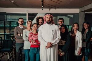 un' diverso gruppo di riuscito attività commerciale persone nel un' moderno bicchiere ufficio In piedi insieme a il superiore con loro arabo capo direttore foto