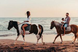 il famiglia spende tempo con loro bambini mentre equitazione cavalli insieme su un' sabbioso spiaggia. selettivo messa a fuoco foto