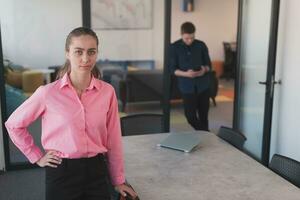 ritratto di giovane sorridente attività commerciale donna nel creativo Aperto spazio coworking avviare ufficio. riuscito donna d'affari in piedi nel ufficio con copyspace. collaboratori Lavorando nel sfondo. foto