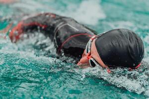 un' triatleta nel un' professionale nuoto completo da uomo treni su il fiume mentre preparazione per olimpico nuoto foto