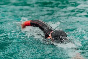 un' triatleta nel un' professionale nuoto completo da uomo treni su il fiume mentre preparazione per olimpico nuoto foto