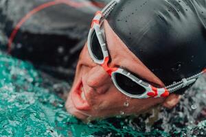 un' triatleta nel un' professionale nuoto completo da uomo treni su il fiume mentre preparazione per olimpico nuoto foto