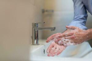 uomo utilizzando sapone e lavaggio mani sotto il acqua rubinetto. igiene concetto mano avvicinamento dettaglio. foto