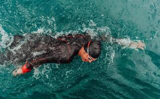 un' triatleta nel un' professionale nuoto completo da uomo treni su il fiume mentre preparazione per olimpico nuoto foto