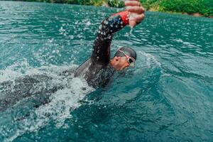 un' triatleta nel un' professionale nuoto completo da uomo treni su il fiume mentre preparazione per olimpico nuoto foto