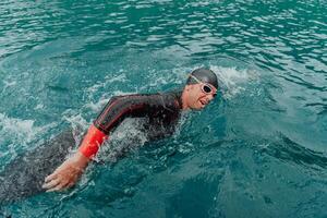 un' triatleta nel un' professionale nuoto completo da uomo treni su il fiume mentre preparazione per olimpico nuoto foto