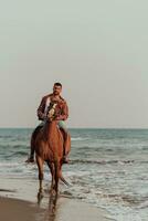 un' moderno uomo nel estate Abiti gode equitazione un' cavallo su un' bellissimo sabbioso spiaggia a tramonto. selettivo messa a fuoco foto