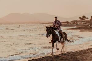 un' moderno uomo nel estate Abiti gode equitazione un' cavallo su un' bellissimo sabbioso spiaggia a tramonto. selettivo messa a fuoco foto