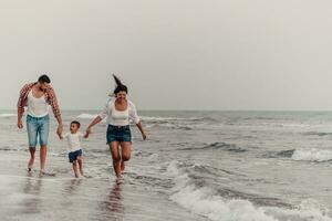 il famiglia gode loro vacanza come essi camminare il sabbioso spiaggia con loro figlio. selettivo messa a fuoco foto