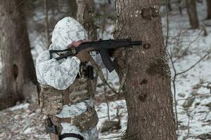 inverno guerra nel il artico montagne. operazione nel freddo condizioni.soldato nel inverno mimetizzato uniforme nel moderno guerra esercito su un' neve giorno su foresta campo di battaglia con un' fucile. selettivo messa a fuoco foto