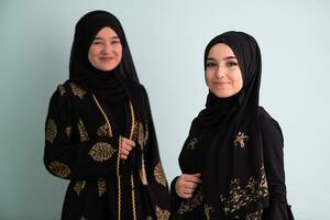 Due bellissimo musulmano donna nel alla moda vestito con hijab isolato su moderno ciano sfondo che rappresentano concetto di moderno Islam e Ramadan kareem foto